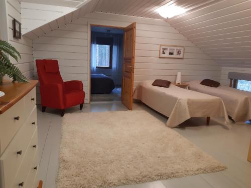 a bedroom with two beds and a red chair at Topin Tupa 1 in Oravisalo