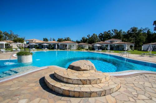 een groot zwembad met een vuurplaats in een tuin bij Limone Beach Resort in Castiadas