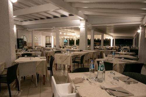 una sala da pranzo con tavoli e sedie bianchi di Limone Beach Resort a Castiadas