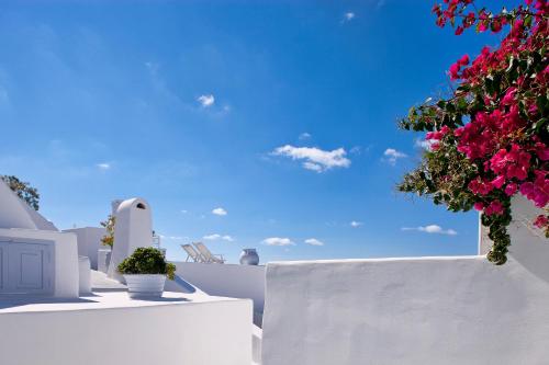 a view of a white building with flowers on it at Cliff Side Suites in Firostefani
