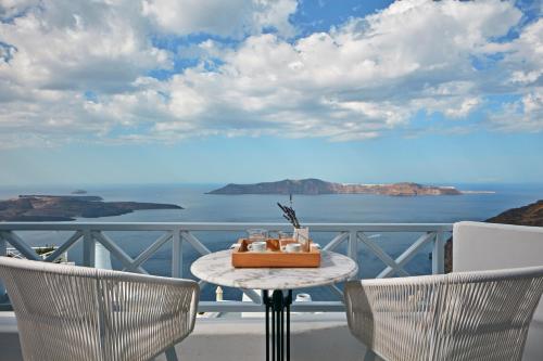 a table on a balcony with a view of the ocean at Cliff Side Suites in Firostefani