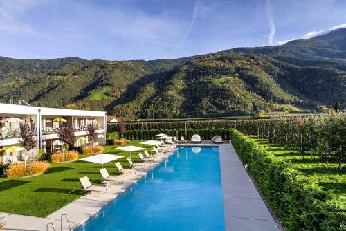 a hotel with a swimming pool and mountains in the background at Residence & Sportlodges Claudia in Plaus