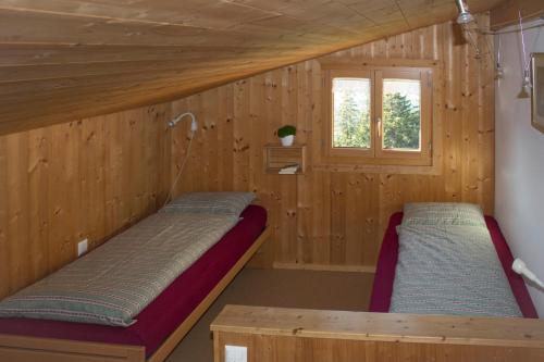 2 łóżka w drewnianym pokoju z oknem w obiekcie La Casa Cathomen Brigels - Maiensäss/Berghaus für max. 6 Personen w mieście Breil/Brigels