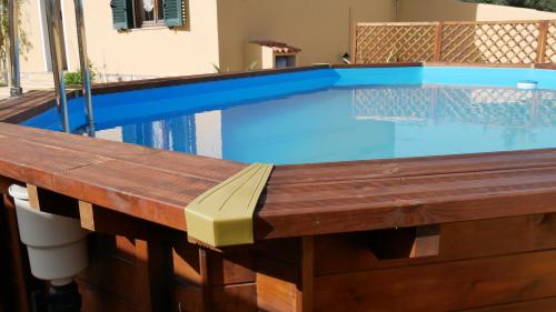 a swimming pool with a wooden deck and a wooden table at B&B Del Viale in Bacu Abis