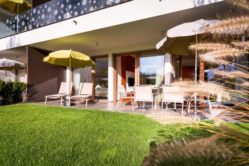 a patio with chairs and tables and umbrellas at Residence & Sportlodges Claudia in Plaus