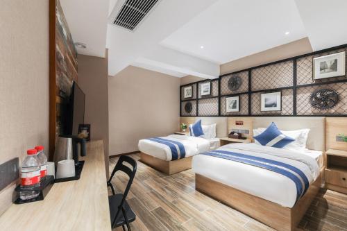 a hotel room with two beds and a television at Zou Qu Ye Travel Hotel in Chongqing
