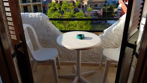 d'une petite table et de chaises sur un balcon avec fenêtre. dans l'établissement Nancy's Rooms 2, à Gouviá