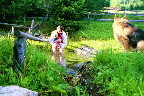 a woman sitting in the water with a dog at Bauernhof Marx in Gaal