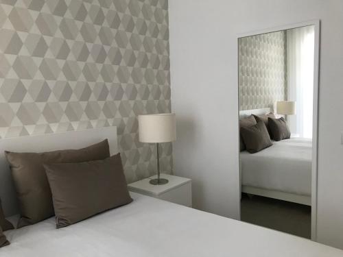 Un dormitorio blanco con una cama y un espejo. en Lisbon10, en Lisboa