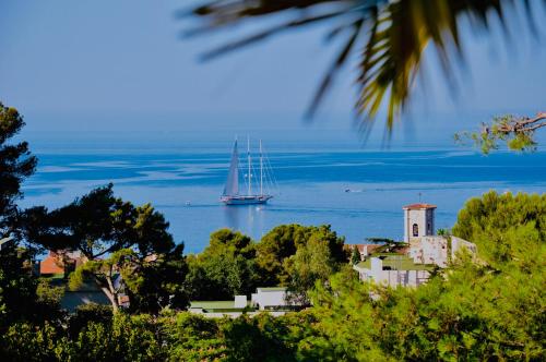 a sail boat in the water next to a small town at THE ADDRESS CASSIS in Cassis