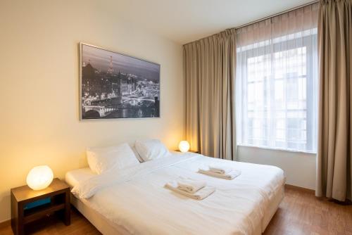 um quarto de hotel com uma grande cama branca e uma janela em EU Parliament Terrace Residence em Bruxelas