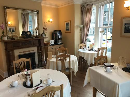a dining room with two tables and a fireplace at Portland House in Keswick