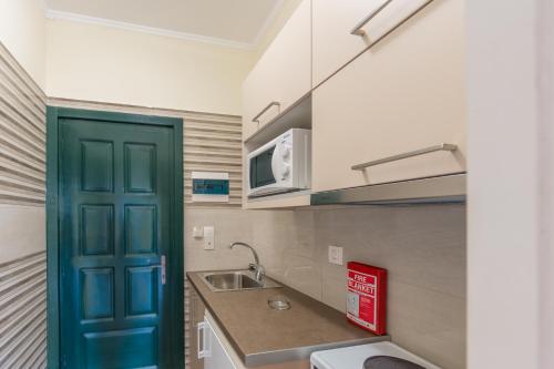 a kitchen with a blue door and a sink at Chandris Apartments in Kavos