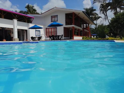 a villa with a swimming pool in front of a house at Finca Hotel la Manuela in Armenia