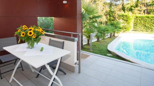 a vase of sunflowers on a table next to a pool at Villa Riva Beachfront in Lignano Sabbiadoro