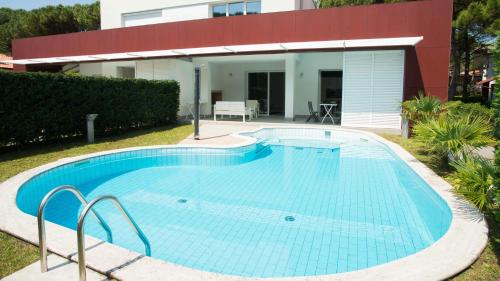a large swimming pool in front of a house at Villa Riva Beachfront in Lignano Sabbiadoro