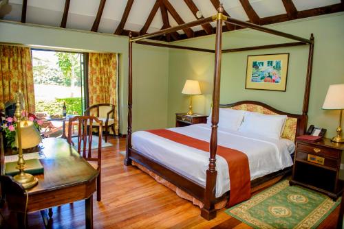a bedroom with a four poster bed and a table at Windsor Golf Hotel & Country Club in Nairobi