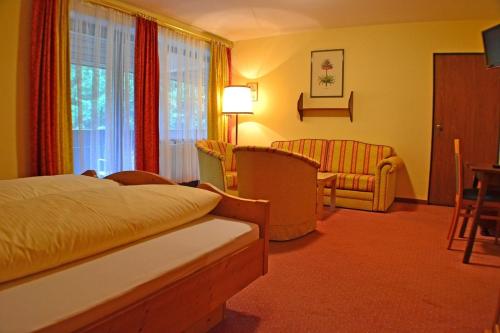 ein Hotelzimmer mit einem Bett und einem Stuhl in der Unterkunft Hotel Mooserkreuz in Sankt Anton am Arlberg