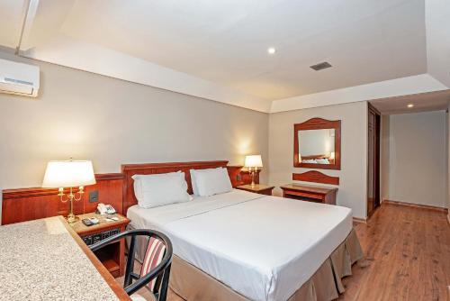a bedroom with a bed and a table and a mirror at Rede Andrade Braz in Curitiba