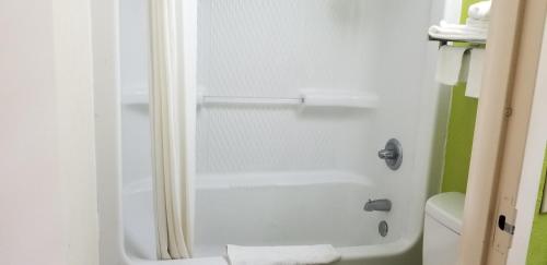 a bathroom with a shower with a white tub at Super 8 by Wyndham Ruther Glen Kings Dominion Area in Ruther Glen
