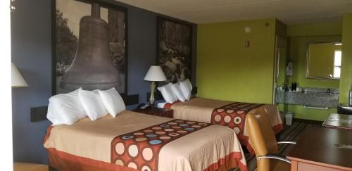 two beds in a hotel room with green walls at Super 8 by Wyndham Ruther Glen Kings Dominion Area in Ruther Glen
