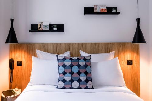 a bedroom with a bed with a wooden headboard at 9Hotel Bastille-Lyon in Paris