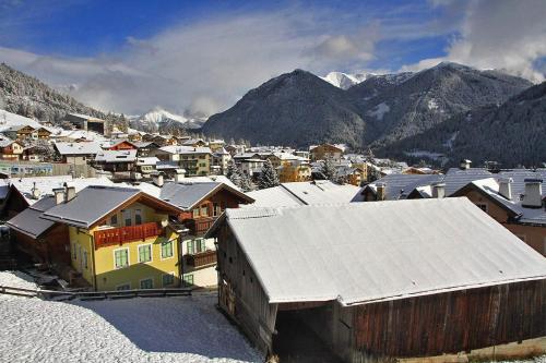 una pequeña ciudad con edificios nevados y montañas en Villetta Clara, en Vigo di Fassa