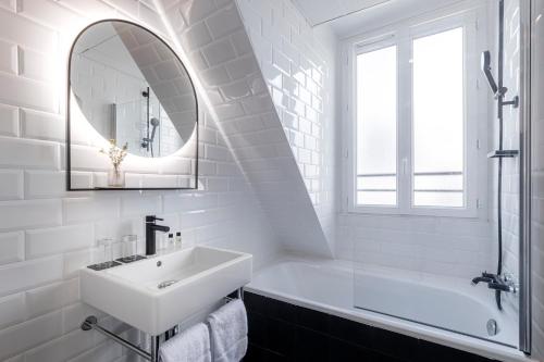 a white bathroom with a sink and a mirror at 9Hotel Bastille-Lyon in Paris