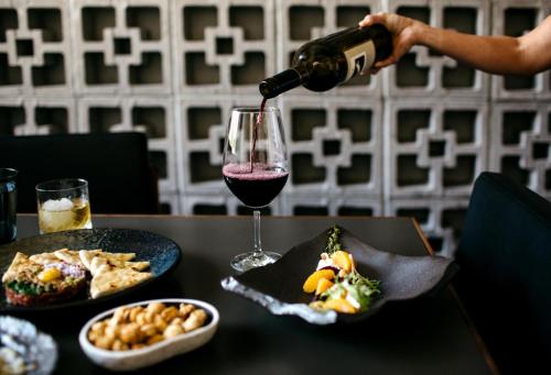 a person pouring wine into a glass on a table with food at Fairmont Scottsdale Princess in Scottsdale