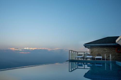 a house on the water with chairs on the deck at Sarangkot Mountain Lodge in Pokhara