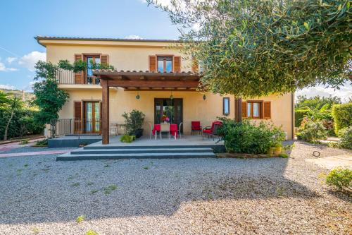 a house with a patio with red chairs in front of it at B&B Le Dune - Self Check in in Lascari