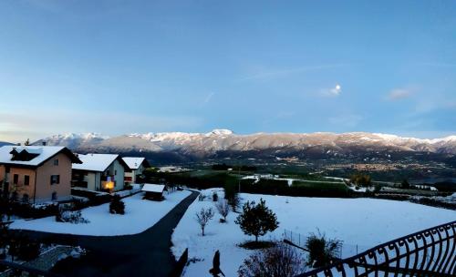a house covered in snow with mountains in the background at Affittacamere Dolce Sogno in Coredo