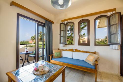 a living room with a blue couch and windows at Evangelos Apartments in Platanias