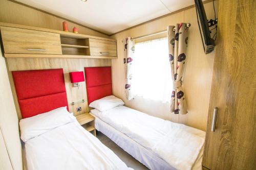 two beds in a small room with a window at River Lodge Platinum Plus Holiday Home with River Views, Free Wifi & Netflix in Camber