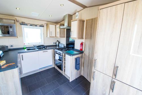 a kitchen with white cabinets and a stove top oven at River Lodge Platinum Plus Holiday Home with River Views, Free Wifi & Netflix in Camber