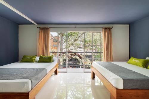 2 camas en una habitación con ventana grande en Ayenda 1405 Ibiza, en Cali