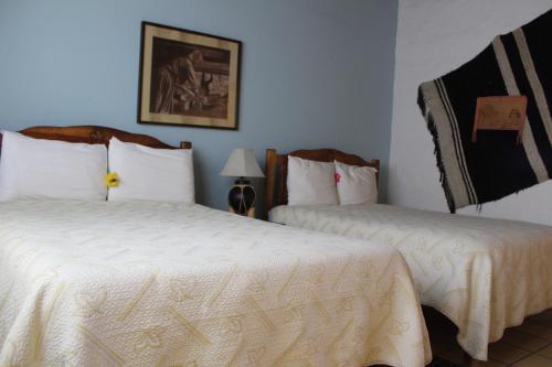 a bedroom with two beds and a picture on the wall at Hotel Paraiso del Oso in Cerocahuí