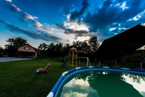 einen Hinterhof mit Pool und Spielplatz in der Unterkunft PENSIUNEA SURYA in Ludeştii de Jos