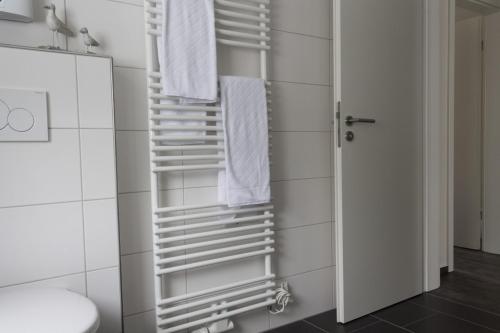 Un baño con toallas blancas colgando de un toallero. en Haus Am Lagunenbad Ferienwohnung Ettelsberg, en Willingen