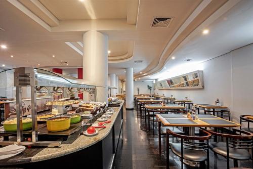 a restaurant with tables and chairs and a buffet at Rede Andrade Braz in Curitiba