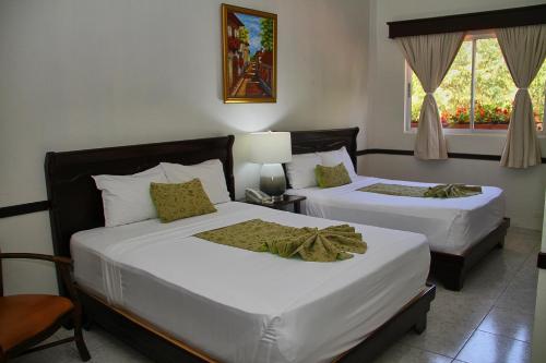 a bedroom with two beds and a window at Platino Hotel & Casino in Santiago de los Caballeros