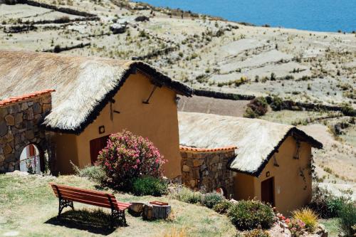 a bench in front of a building with a grass roof at Ecolodge La Estancia in Comunidad Yumani