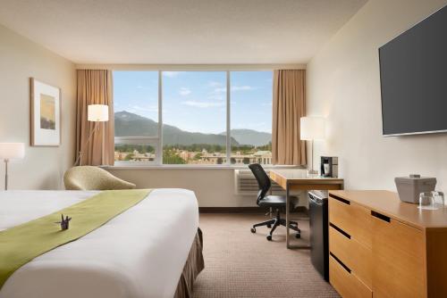 a hotel room with a bed and a desk and a window at Coast Chilliwack Hotel by APA in Chilliwack