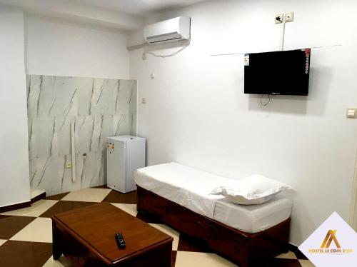 a small room with a bed and a tv at Hostel le Coin d'Or in Fort de lʼEau