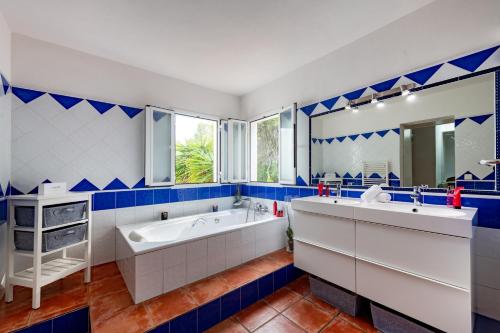 La salle de bains bleue et blanche est pourvue d'une baignoire et d'un lavabo. dans l'établissement Villa Mercedes, à Cala Llonga