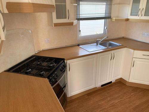 a small kitchen with a stove and a sink at Chapel Caravans PS12A in Chapel Saint Leonards