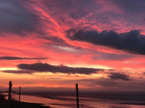 a sunset over the water with poles in the foreground at The Waterside Rooms in Annan