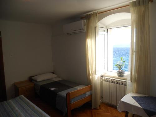 a bedroom with a bed and a window with the ocean at Room Dinko in Valun