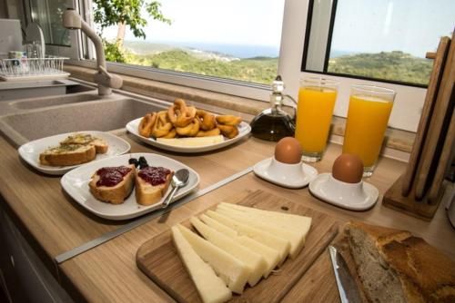 a kitchen counter with plates of food and two glasses of orange juice at Olea Escape Villa in an Olive Estate in Gythio