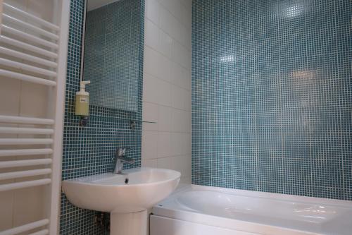 a bathroom with a sink and a toilet and blue tiles at Orange Onix Apartaments in Bucharest